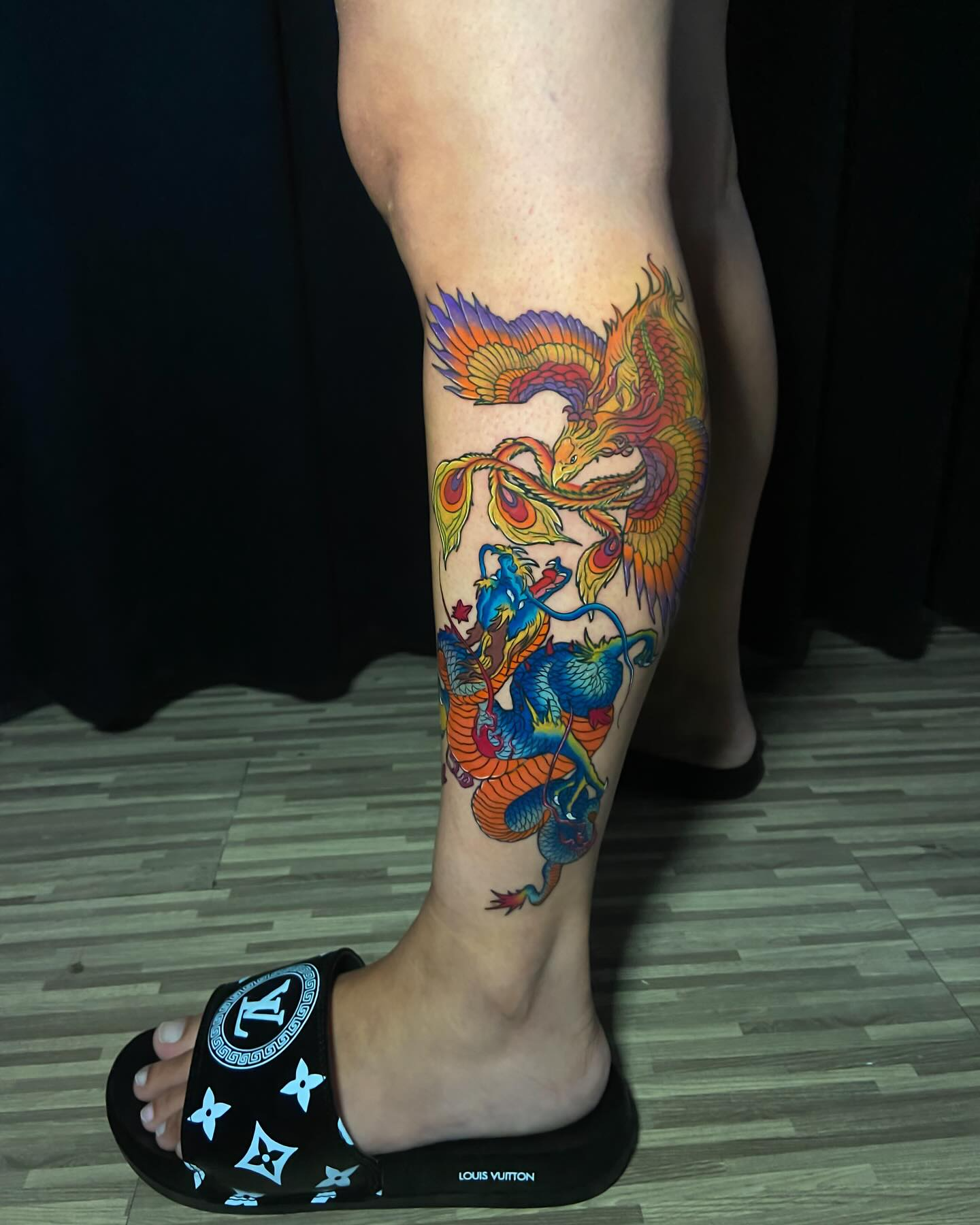 Phoenix and Dragon tattoo on the Calf by Expert Ink Bali, showcasing intricate shading and fine detailing.